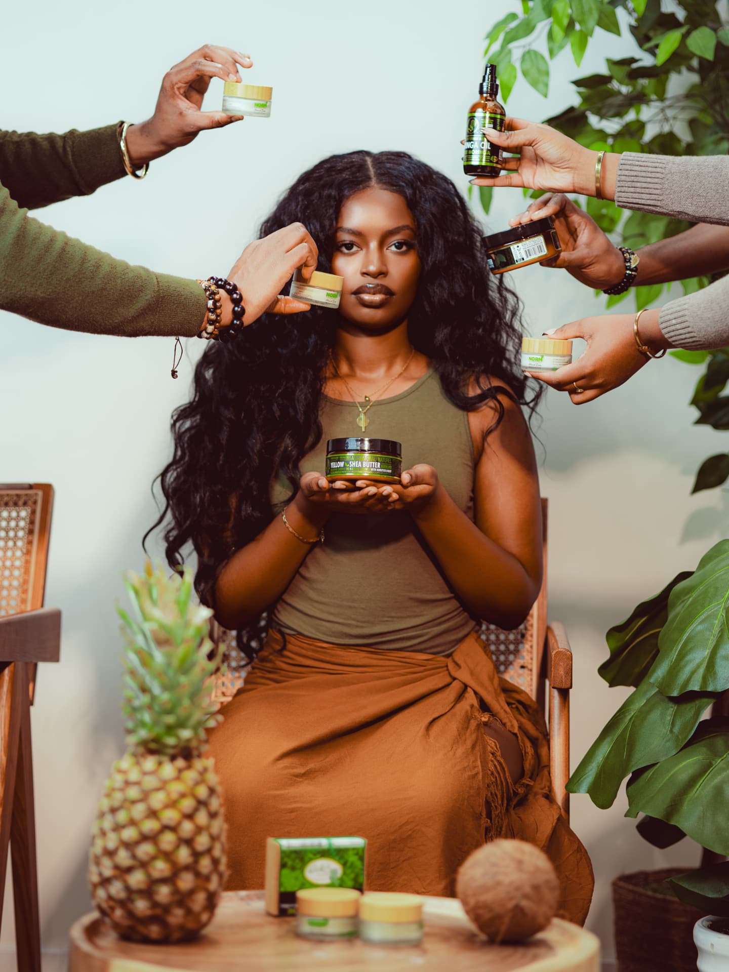 A Black woman surrounded by hands offering culturally rooted beauty products